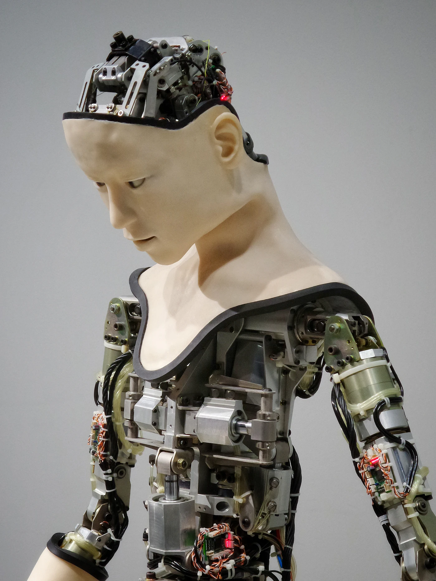 Humanoid robot with its chest and arm covers removed, showing actuators, wiring and circuit boards
