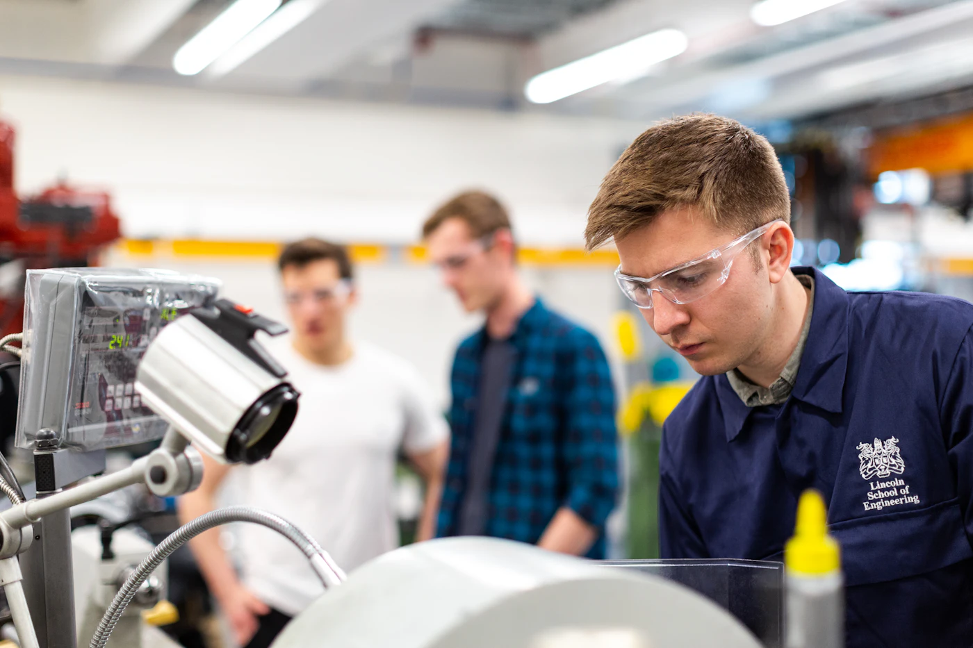 Engineers in safety glasses reviewing a machine in a workshop