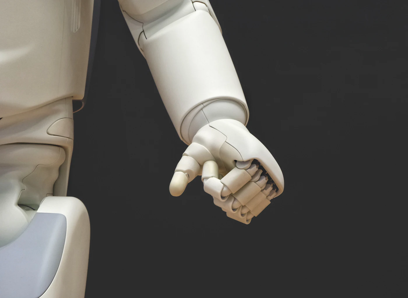 White robotic arm and hand held relaxed against a dark background